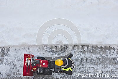 Worker cleaning snow on the sidewalk with a snowblower. Wintertime Editorial Stock Photo