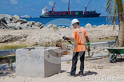 Worker cleans shovel by knocking it on stone Editorial Stock Photo