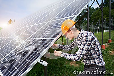 Worker connects solar panels on a green plantation. Home construction. Stock Photo