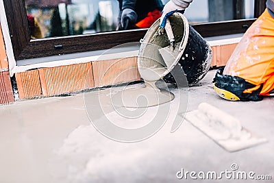 Worker on construction site pouring sealant from bucket for waterproofing cement Stock Photo