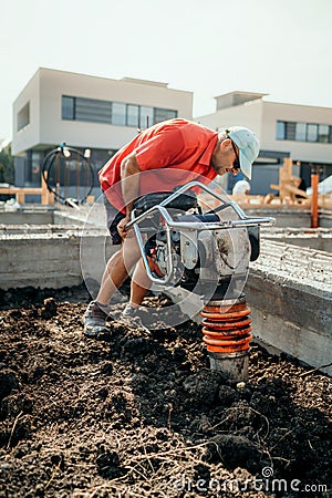 Worker on construction site with vibratory compactor for soil compacting or earth rammer Stock Photo