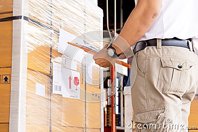 Worker courier holding clipboard writing on checklist for delivering shipment pallet goods Stock Photo