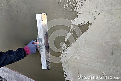 Worker covering insulated wall with solution of glue over plastered styrofoam insulation Stock Photo