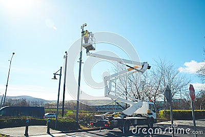 Worker on the crane equipped with safety equipment install a video surveillance system. Editorial Stock Photo