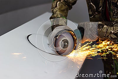 worker cuts a circle in metal with an angle grinder Stock Photo