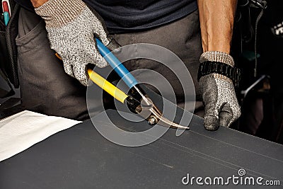 A worker cuts a sheet of roofing iron with metal scissors Stock Photo