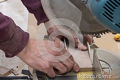 A worker cuts a wooden billet on a floor machine with a circular saw. Concept: woodworking, sawing of materials, violation of safe Stock Photo