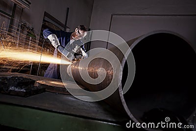 Worker cutting pipe with angle grinder. Stock Photo