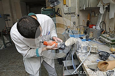 Worker cutting wooden blank with a hand cutting machine, manufacturing prosthesis Editorial Stock Photo
