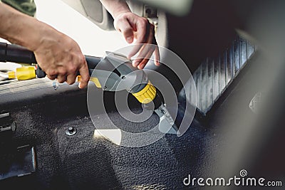 worker, detailer vacuuming carpet of car interior, using steam vacuum Stock Photo