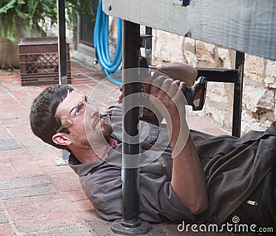 Worker Drilling Hole in Awkward Place Stock Photo