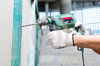 Worker drilling with machine in construction site wall Stock Photo