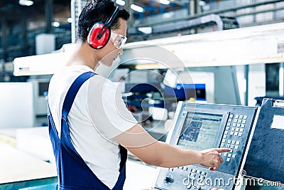 Worker entering data in CNC machine at factory Stock Photo