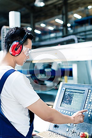 Worker entering data in CNC machine at factory Stock Photo
