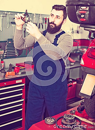 Worker examines a broken motorcycle part Stock Photo