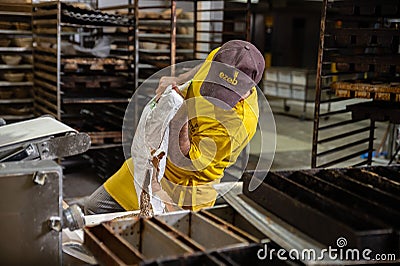 Worker in ezeb bakery while putting the ingredients to get to work and surrounded by the shelves Editorial Stock Photo