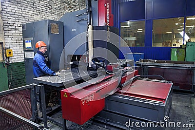 Worker follows the work of machine for drilling steel plates. Editorial Stock Photo
