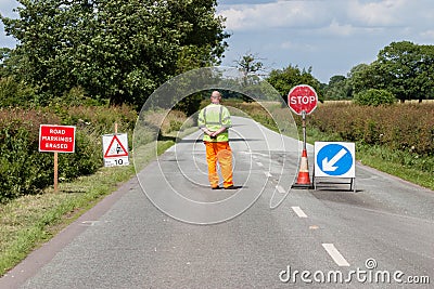 Worker in front of road closed signs on a UK road Editorial Stock Photo