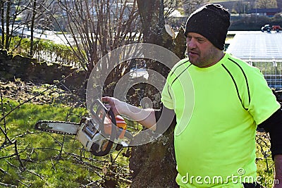 Worker in the garden with a chainsaw. Stock Photo