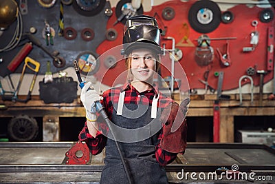 Worker girl welder on steel structure in factory, light spark Stock Photo