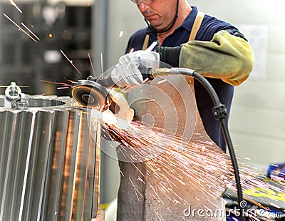 worker with a grinding machine processes a gear wheel - production of gears in a modern factory for mechanical engineering Stock Photo