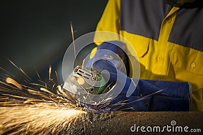 The worker grinding metal in manufacturing plant, sparks flying Stock Photo