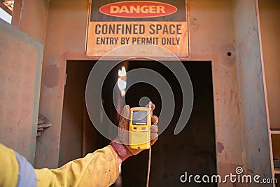 Worker hand holding gas test leak detector device at main confined space entry and exit Stock Photo