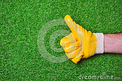 Worker hand in a yellow glove with a thumbs up gesture. Stock Photo