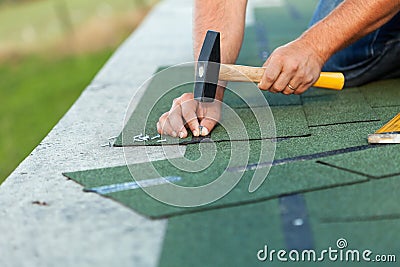 Worker hands installing bitumen roof shingles Stock Photo