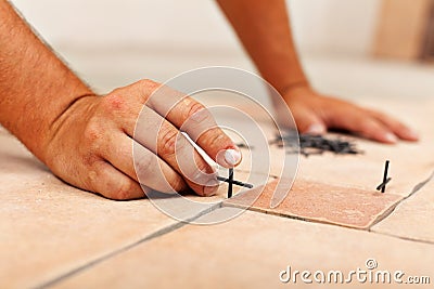 Worker hands placing spacers between ceramic floor tiles Stock Photo