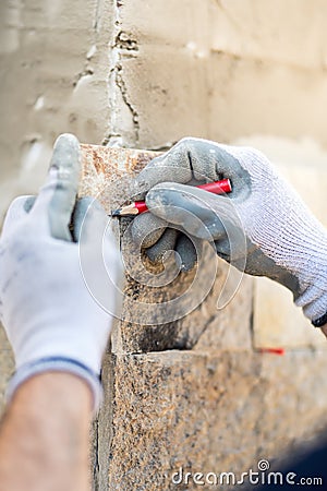 worker hands taking notes and drawing on stone. Construction worker paving home facade with stone Stock Photo