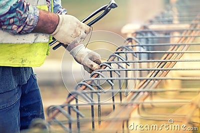 Worker hands using steel wire and pliers to secure bars on construction site Stock Photo