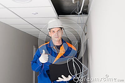 A worker has successfully completed setting up a secure internet in the building using a laptop Stock Photo