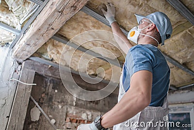 Worker in His 30s Replacing Old Attic Mineral Wool Insulation Stock Photo