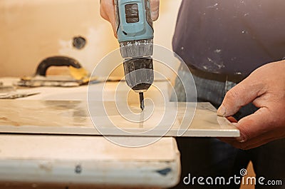 Worker is holding in hands electric drill and cutting panels in apartment. Maintenance repair works renovation in the flat with Stock Photo