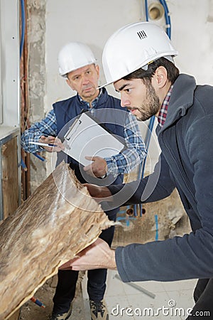 worker holding insulation sheet from wall Stock Photo