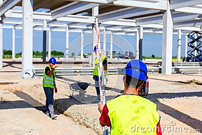 Worker is holding leveling rod to measuring level on construction site Editorial Stock Photo
