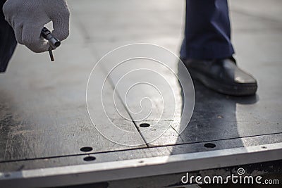 Worker holds bolt. Man tightens screw. Guy assembles structure. Fitting to hole Stock Photo