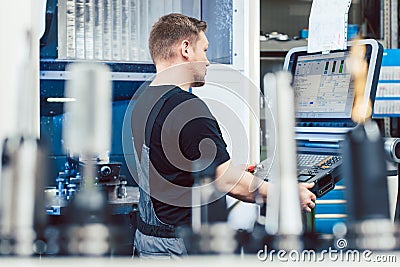 Worker in industrial workshop programming a cnc lathe Stock Photo