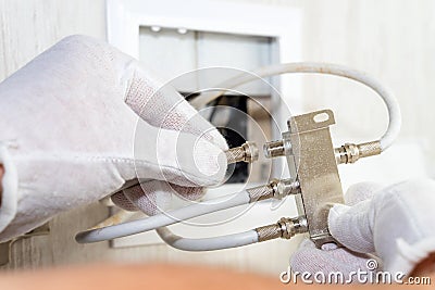 Worker inserts connector of a TV antenna coaxial cable to a splitter. Stock Photo