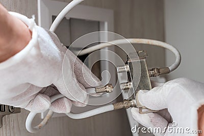 Worker inserts connector of a TV antenna coaxial cable to a splitter. Stock Photo