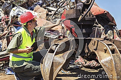 Worker inspect crane on junkyard. Stock Photo