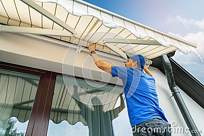 Worker install an awning on the house wall over the terrace Stock Photo