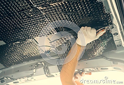 Worker installation soundproofing material to inside of car roof. Sound insulation for auto tuning Stock Photo