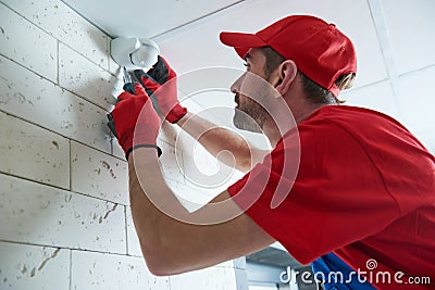Worker installing or adjusting motion sensor detector on the ceiling Stock Photo