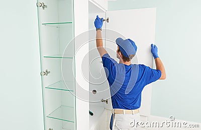 Installer contractor at furniture assembling work. Worker installing bathroom cupboard. Stock Photo