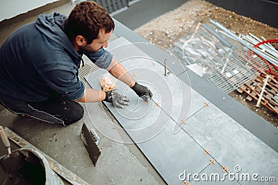 worker installing ceramic tiles on exterior floor and applying mortar with trowel Stock Photo