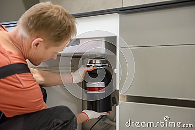 The worker is installing a household waste shredder Stock Photo