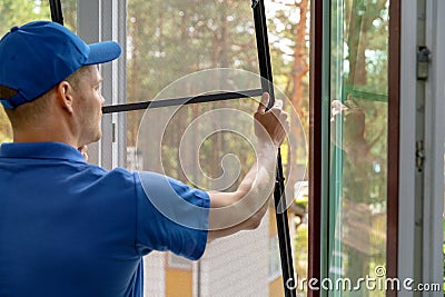 Worker installing mosquito net wire mesh in plastic window frame Stock Photo