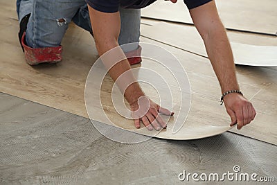 Work on laying flooring. Worker installing new vinyl tile floor. Stock Photo